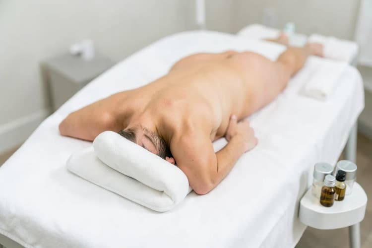 Pessoa deitada em maca de massagem com óleos essenciais